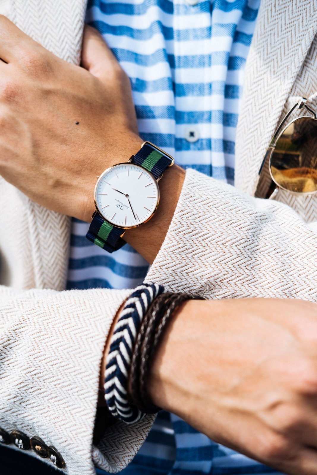 Armbanduhr und Armbänder neben einem karierten Hemd