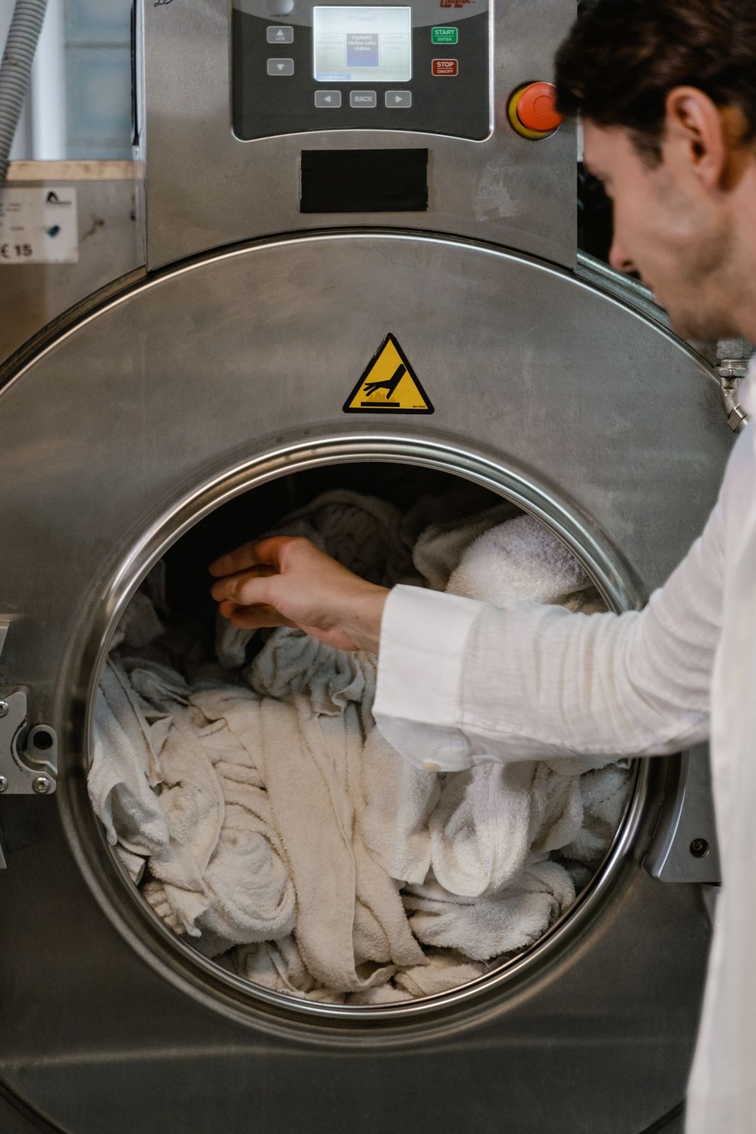 Helle Kleidung wird in eine Waschmaschine gelegt