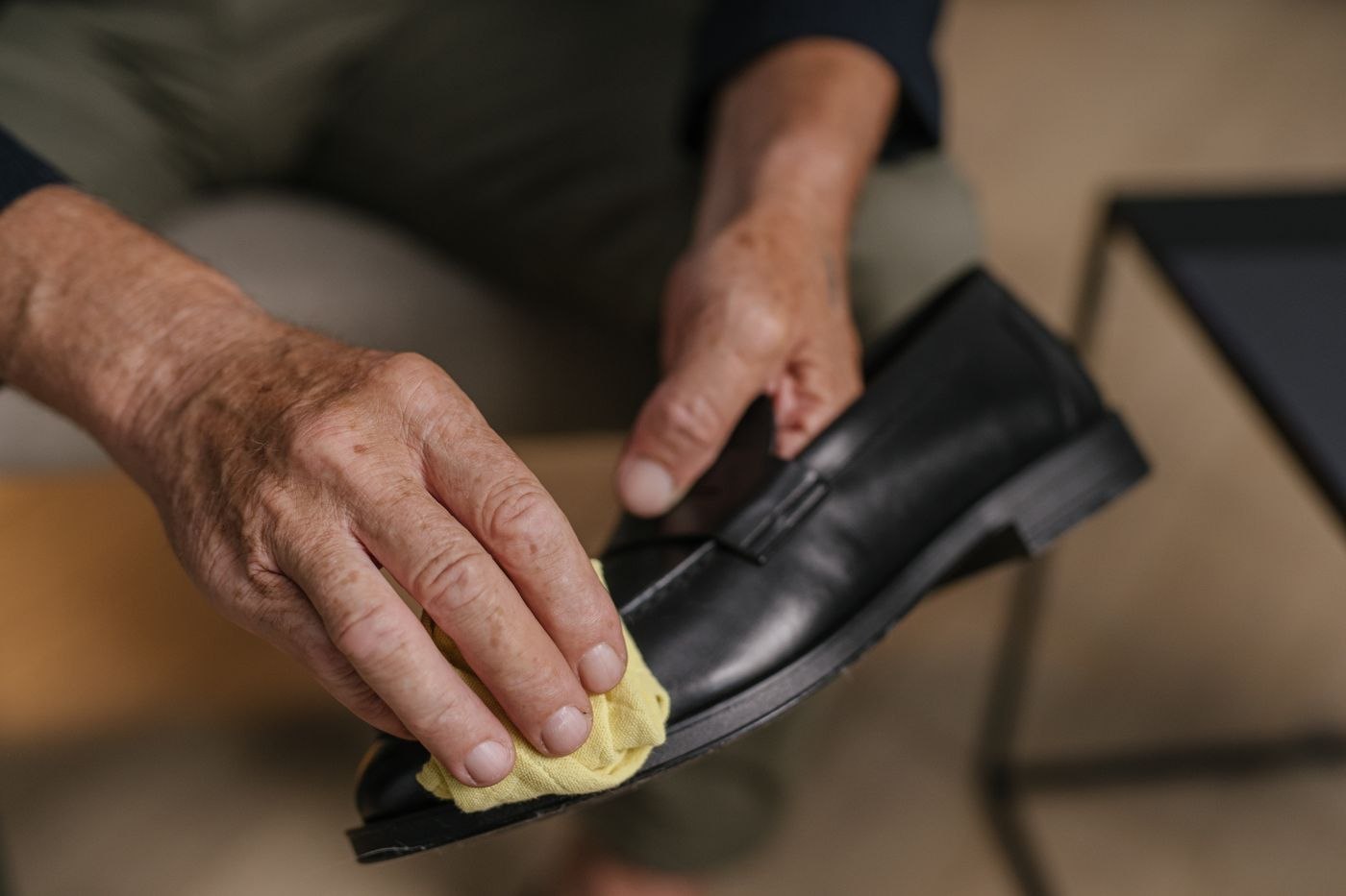 Ein schwarzer Lederschuh wird vorsichtig poliert