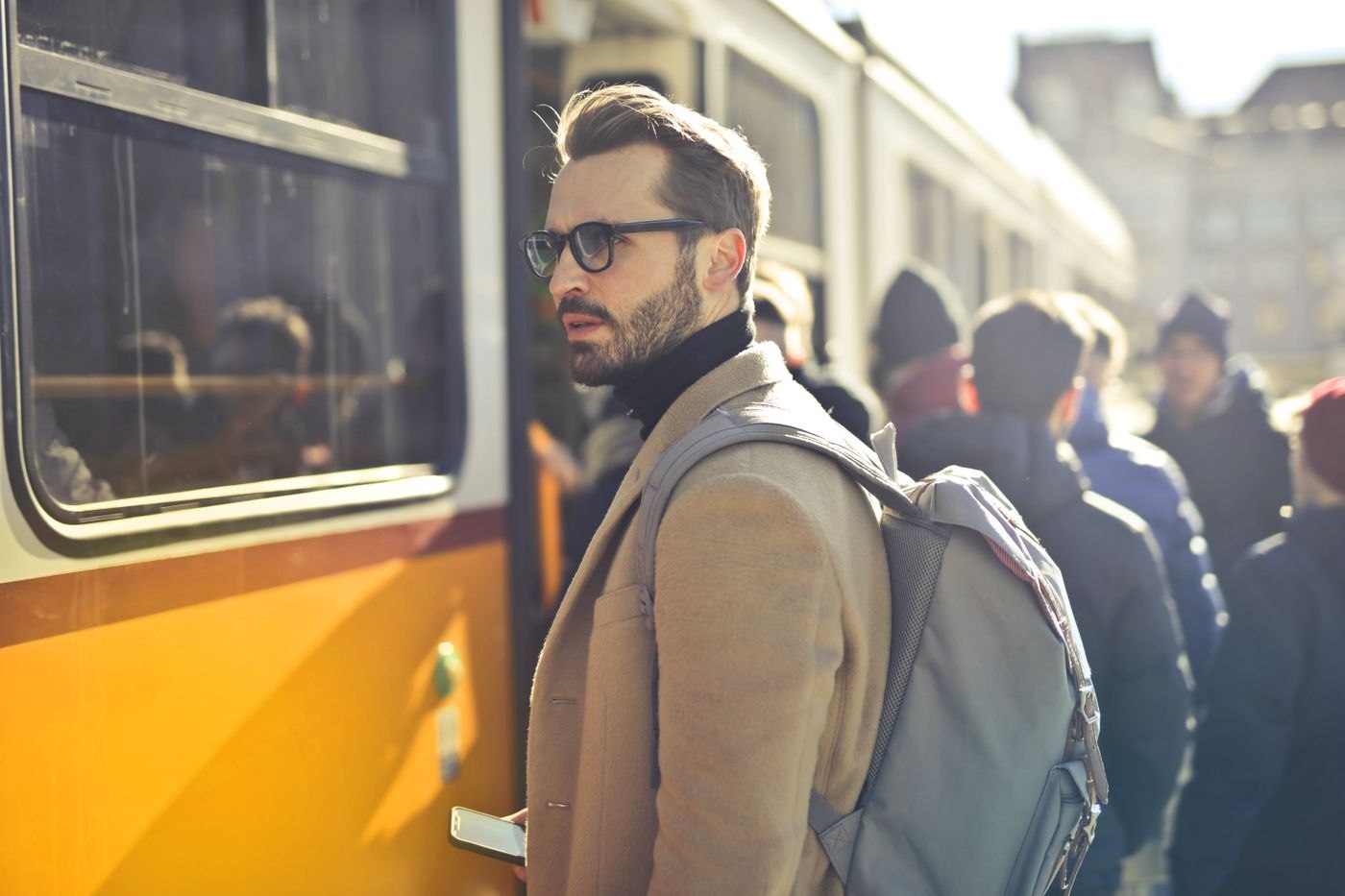 Ein mehrlagiges Outfit mit Rucksack neben einer Straßenbahn