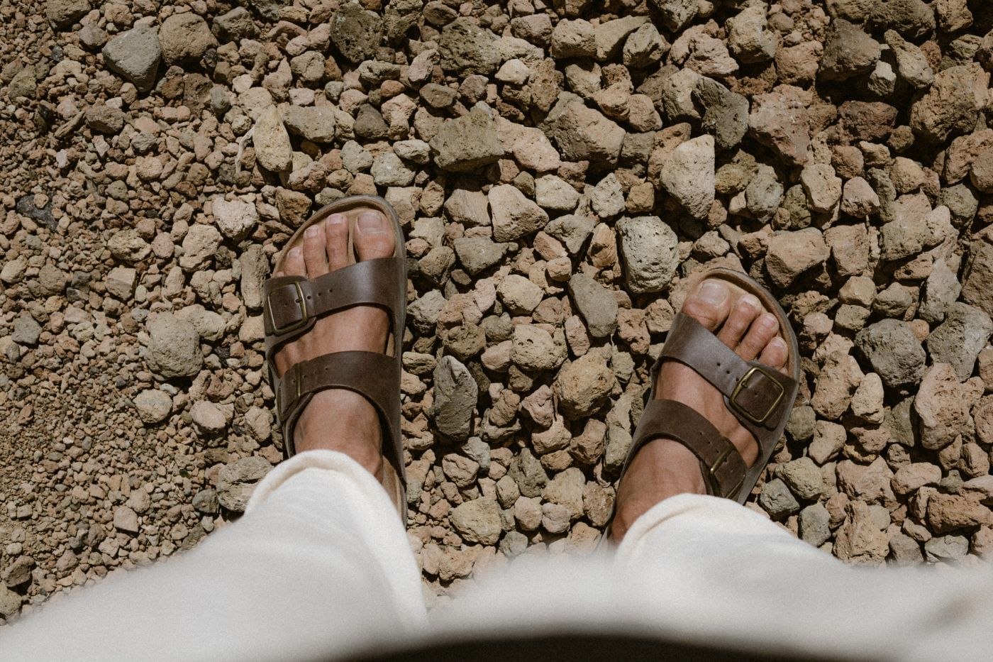 Braune Sandalen unter heller Hose